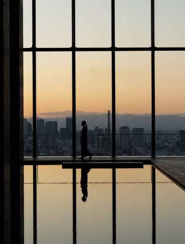 Sunrise reflected in a still pool at Aman Tokyo, viewed through geometric window panes.