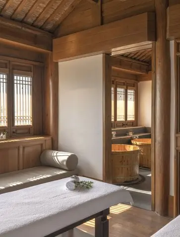 Spa treatment room at Amandayan with wooden interior, soaking tub, and doorway to adjoining space.