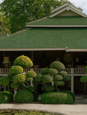 Aman Nai Lert Bangkok heritage home with manicured topiaries lining the entrance pavilion.