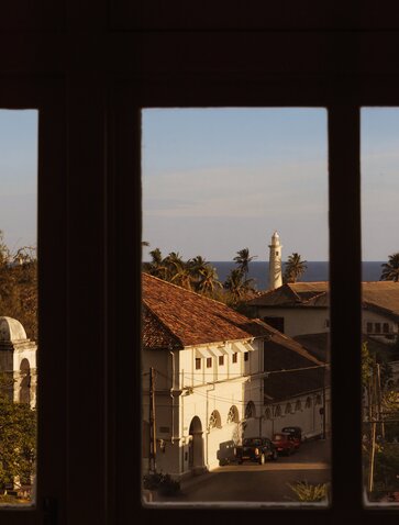 View of Galle Fort and surrounding landscape from Amangalla, framed by dark wooden columns.