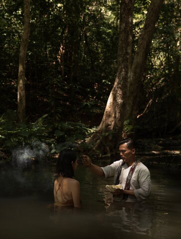 Spa therapist guides guest through a riverside wellness ritual at Amanwana, Indonesia.