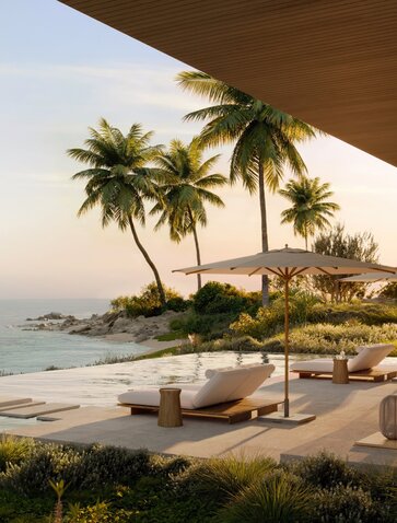 Amancaya pool terrace overlooking the Pacific coast at sunset, with palm trees and loungers.
