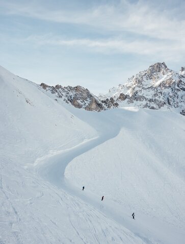 Skiers descend a snow-covered slope at Aman Le Mélézin in the French Alps.