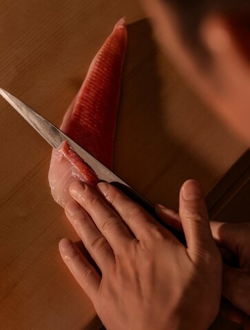 Hands holding a red chilli and sesame ingredient at Amanvari, Bangkok.