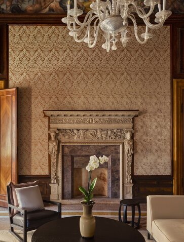 Sansovino Stanza bedroom at Aman Venice hotel, with ornate fireplace and chandelier.