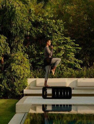 Woman standing on poolside platform at Amanera's fitness casita, overlooking water and lush greenery.