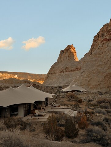 Camp Sarika exterior with traditional structure nestled beneath towering desert rock formations at Amangiri, USA.