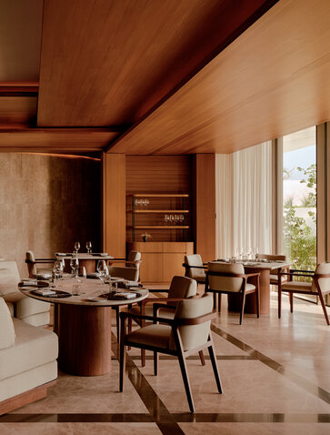 Amanvari lounge with warm timber finishes, mid-century chairs and expansive windows overlooking Mexican landscape.