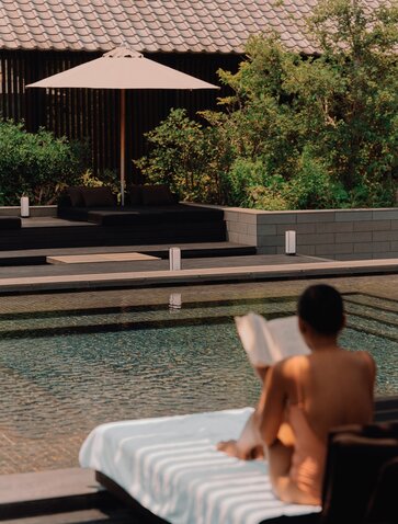 Guest relaxing poolside at Amanemu spa and wellness retreat, Japan.