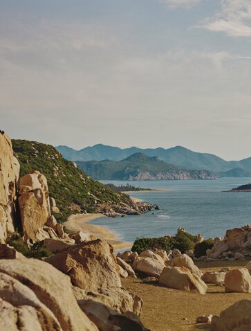 Rocky shoreline at Amanoi overlooking turquoise waters and distant mountains in Vietnam.