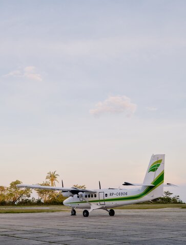 Amanpulo's seaplane on the runway with tropical vegetation in the background.