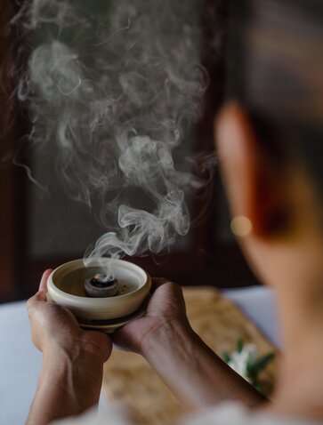 Smoking ceremony ritual at Amanpulo spa, hands holding smouldering bowl with fragrant smoke.