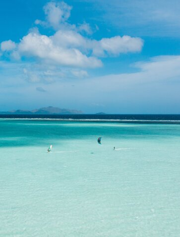Turquoise lagoon at Amanpulo with water sports enthusiasts, Philippines.