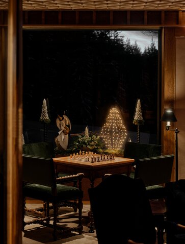 Sapin de Noël illuminé visible depuis une fenêtre d'Aman Le Mélézin, la station en montagne scintille dans la nuit.