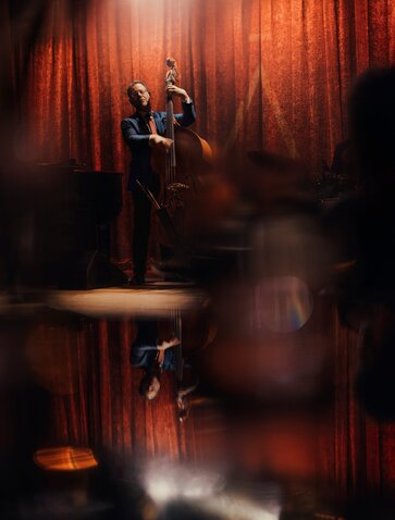 Jazz musician performing on stage at Aman New York's jazz club, bathed in warm red lighting.