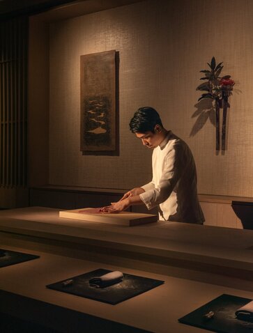 Woman meditating on wooden platform at Aman New York wellness space.