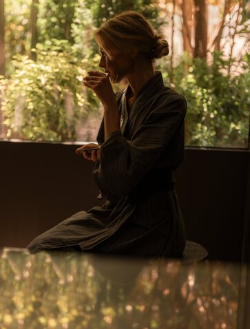 Guest relaxing by a window with garden views at Aman New York spa.