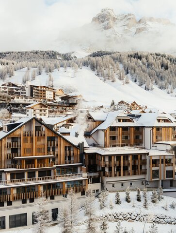 Aman Rosa Alpina exterior in winter, with snow-covered Alpine peaks and traditional mountain architecture.