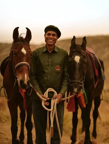 Marwari horse handler holding two saddled horses at Aman-i-Khas, India.