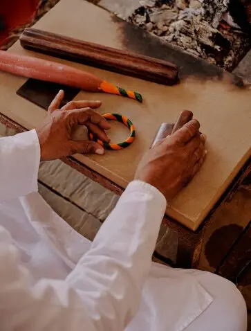 Hands shaping dough on wooden board at Aman-i-Khas, India.