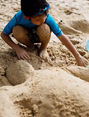 Child building sand castle at Amanwella beach, Sri Lanka.