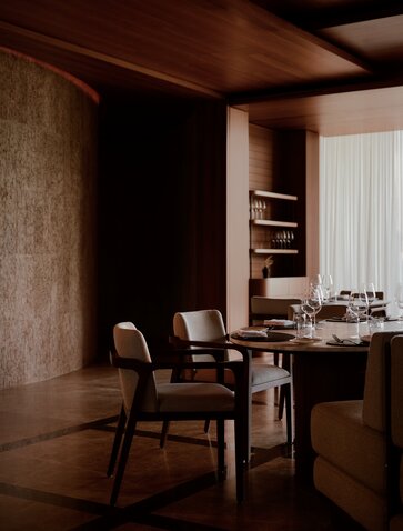 Amanvari dining area with wooden desk, chair, and warm earth-toned walls.