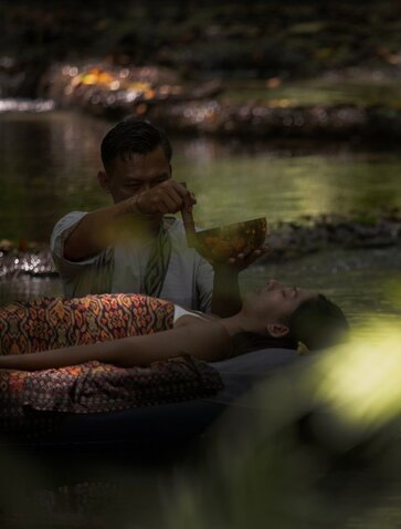 Wellness guide leading floating sound healing session at Diana's Fall, Amanwana, Indonesia.
