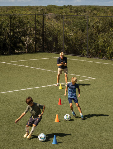 Camp Laurel football pitch at Amanyara resort with young players training outdoors.