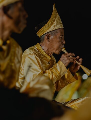 Musician in gold traditional dress performing at Amanwana, Indonesia.