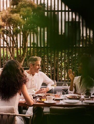 Group of visitors dining together at Arva Terrace, Amanyara, with afternoon light filtering through architectural screens.