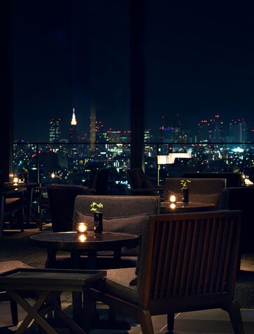 Le Lounge d'Aman Tokyo la nuit, vue sur la ville illuminée depuis la terrasse de l'hôtel.