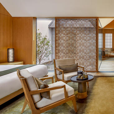 Principal bedroom at Amanyangyun with wooden furnishings, geometric screen partition, and garden views.