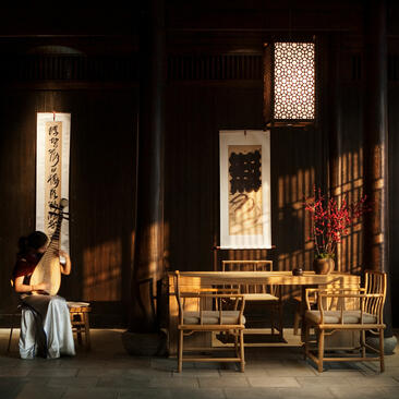 Portrait of Aman Fayun at Amanyangyun, evening interior with warm lighting and traditional wooden furnishings.