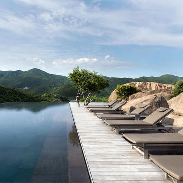 Five-bedroom residence with wooden deck overlooking calm river and mountains at Amanoi, Vietnam.