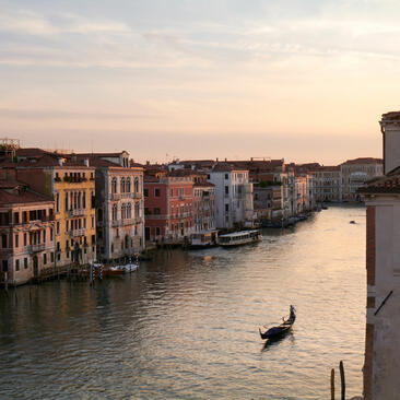 Gondola on the Grand Canal at Aman Venice during sunset, with historic Venetian buildings lining the waterway.
