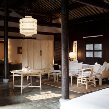 Traditional wooden pavilion at Amanfayun with lantern lighting and simple furnishings in a Chinese village setting.