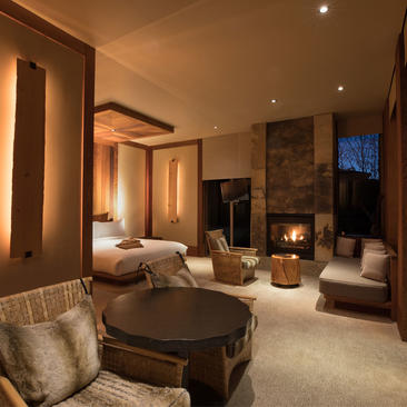 Amangani suite with warm lighting, seating area, and fireplace in the background.