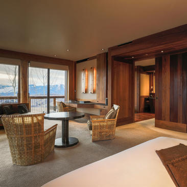 Gros Ventre Suite sitting area at Amangani with woven chairs, mountain views through floor-to-ceiling windows, and wooden interior details.