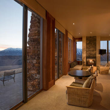 Sena Suite at Amangani with floor-to-ceiling windows overlooking mountain landscape at dusk.