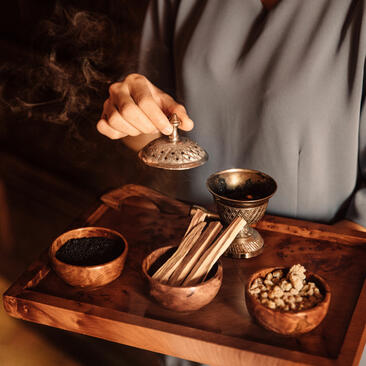 Spa treatment setup at Amanjena with gold-toned vessels and aromatic oils on a wooden tray.