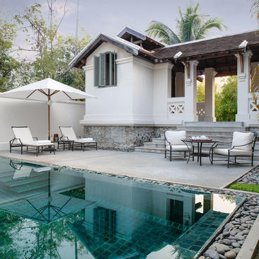 Pool Suite at Amantaka, Laos, with loungers and white umbrellas beside a glass-walled plunge pool.