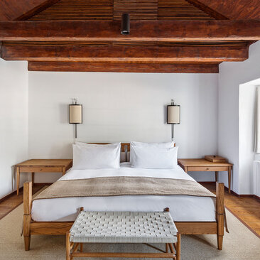 Deluxe Cottage principal bedroom at Aman Sveti Stefan with twin beds and exposed wooden beams.