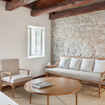 Deluxe cottage seating area at Aman Sveti Stefan with stone feature wall and wooden beams.
