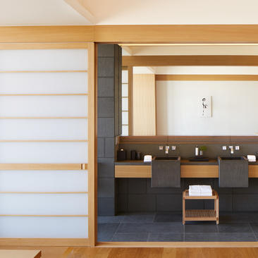 Deluxe Palace Garden View Room bathroom at Aman Tokyo with dark cabinetry and natural wood accents.