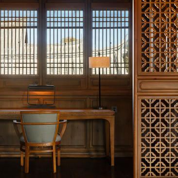 Deluxe Suite at Amandayan with wooden desk, chair, and geometric-patterned screens casting light across walls.