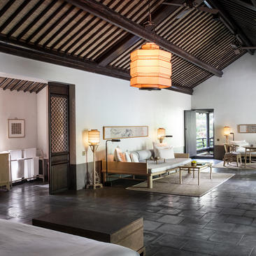 法云安缦度假村豪华村套房内部，采用中式设计元素、木质天花板和石板地面。