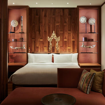 安缦璞瑞度假村的八卧室花园别墅主卧室，木质墙面衬托着白色床品和金色装饰品。