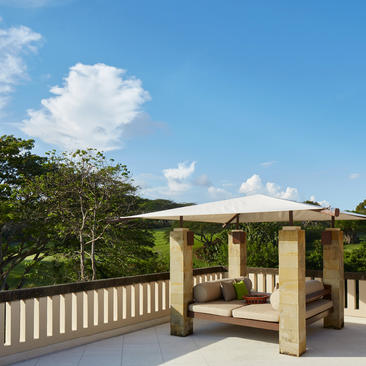 Five-bedroom villa with cream pavilion and wooden railings overlooking tropical gardens at Aman Villas at Nusa Dua, Bali.