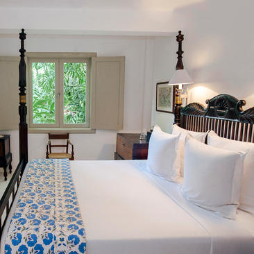 Principal bedroom at Amangalla with twin beds and garden views through arched windows.