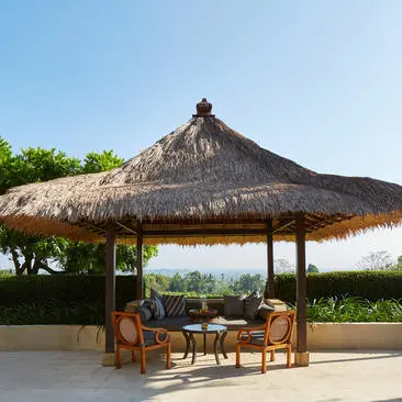 Garden Suite pavilion with thatched roof and wooden seating at Amanjiwo resort, Java, Indonesia.